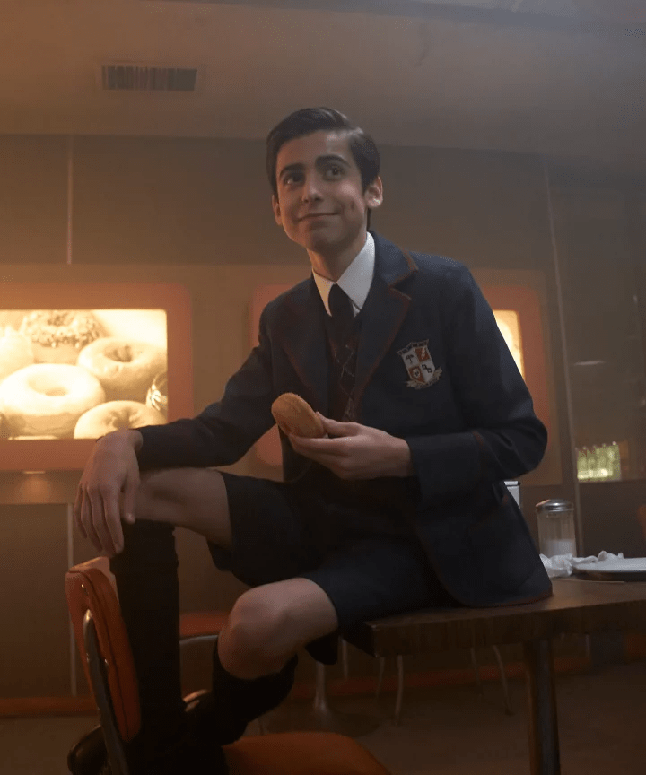 Student in uniform holding donut.